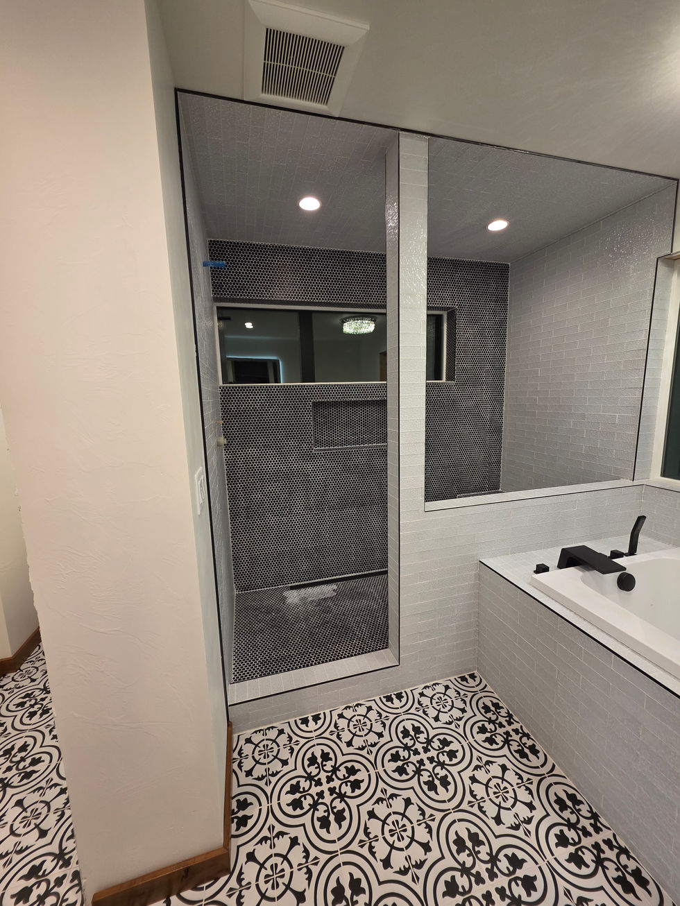 Glass shower panel against penny round mosaic tile beside a subway tiled tub