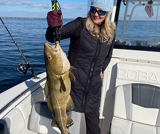 Crew member Summer holding up a freshly caught fish on a fishing charter.