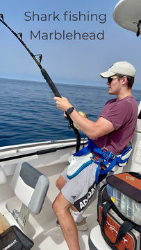 An angler using a harness to reel in a large shark during a deep-sea fishing trip in Marblehead, MA.