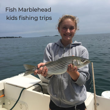 A young angler holding a striped bass during a kid-friendly fishing trip with Fish Marblehead.