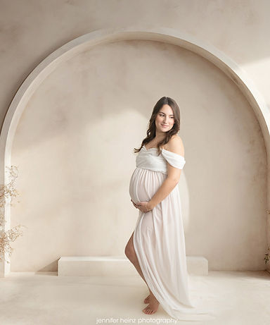 maternity photo shoot with white gown and arched backdrop