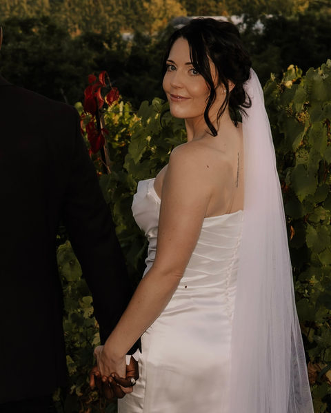 Bridal makeup on a bride outdoors, featuring soft neutral eyeshadow, natural lashes, and a rosy lip, captured from a side profile in her wedding dress and veil.