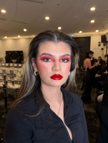 Backstage editorial makeup featuring bold red eye makeup, glossy red lips, and flawless skin created for the Hidden Couture fashion show