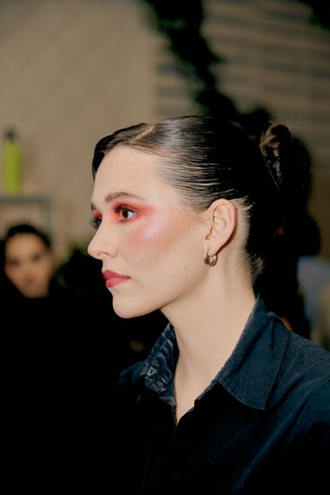 Side profile backstage beauty look featuring editorial pink eye makeup and flawless complexion makeup for Hidden Couture runway show