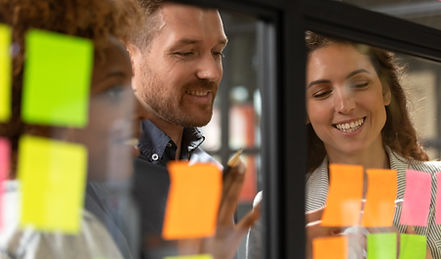 Creative diverse employees team writing ideas on sticky papers on glass wall close up, mul