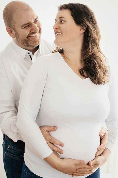 Ehemann und schwangere Frau schauen sich in die Augen