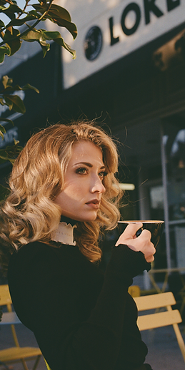 Elegant woman enjoying a handcrafted coffee inside LOKL Café in Morristown, seated by natural light in a warm, cozy setting