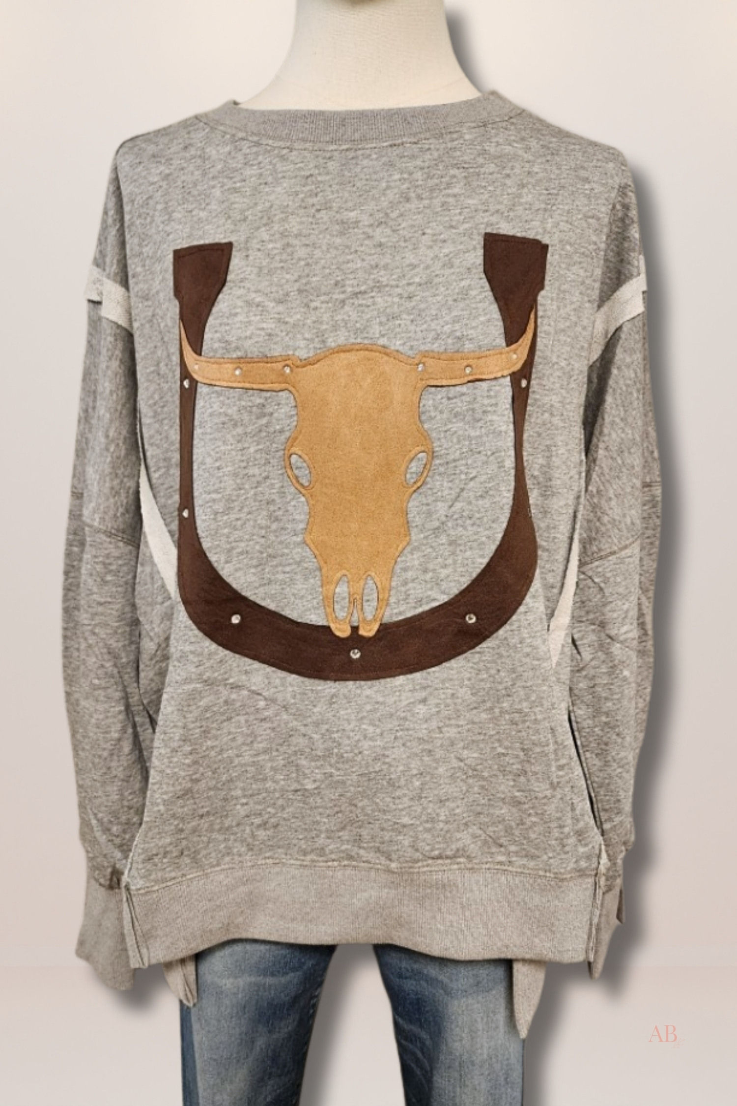 Front view of a heather grey oversized crewneck sweatshirt with a brown longhorn and horseshoe applique on a mannequin.