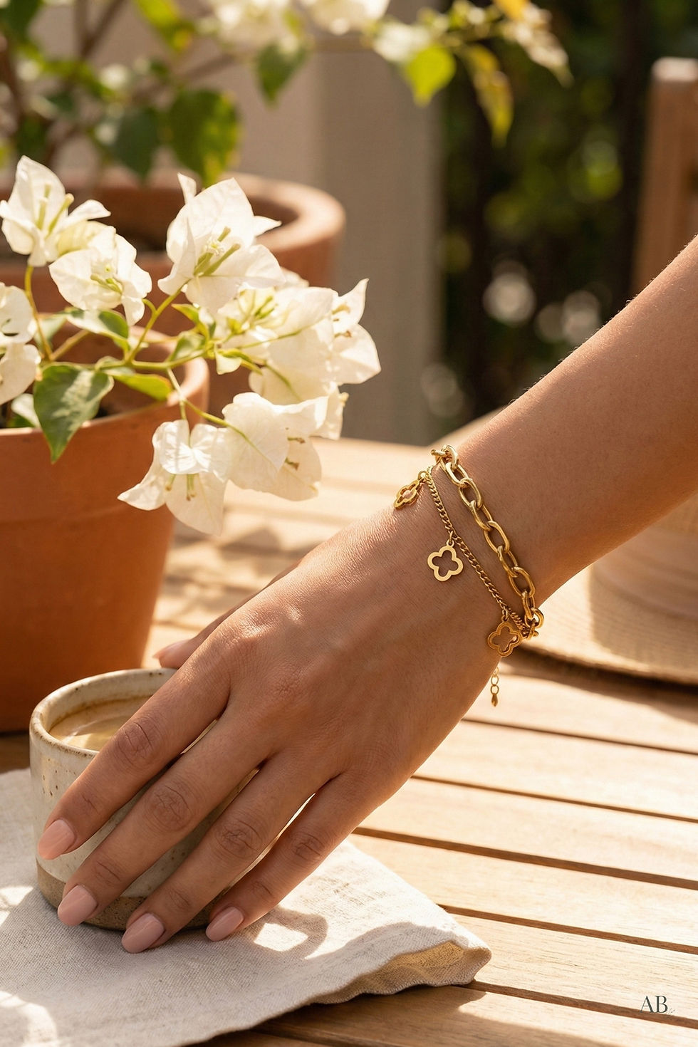 Model wearing a waterproof 18k gold clover bracelet at an outdoor cafe from a Michigan boutique.