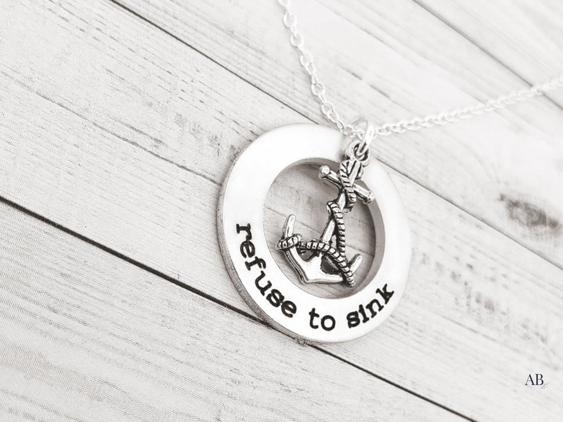 Angled view of the sterling washer and anchor charm on an 18-inch chain over white boards.