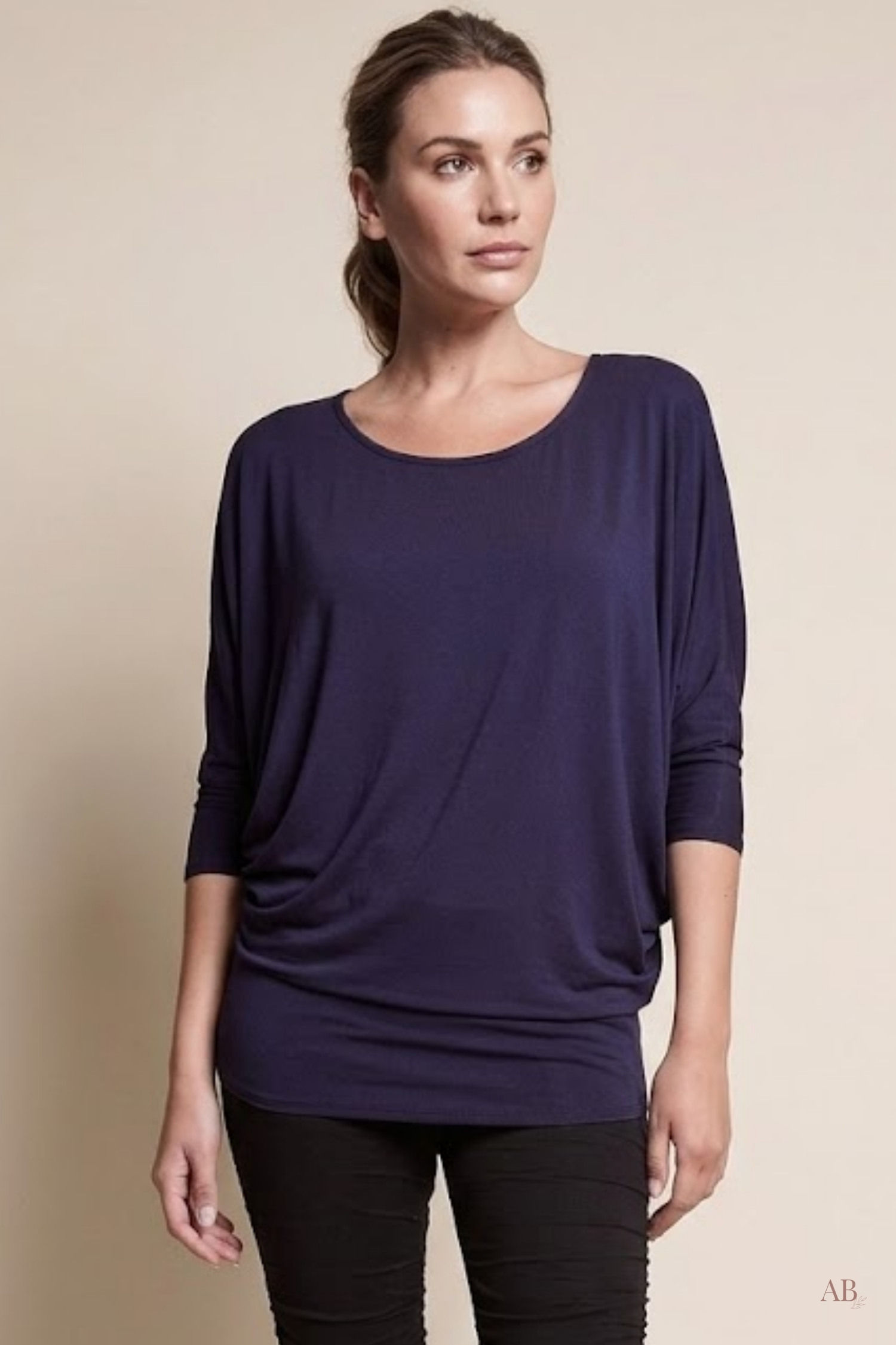 Woman wearing the Navy Blue Arden bamboo dolman top paired with black pants, front studio view.