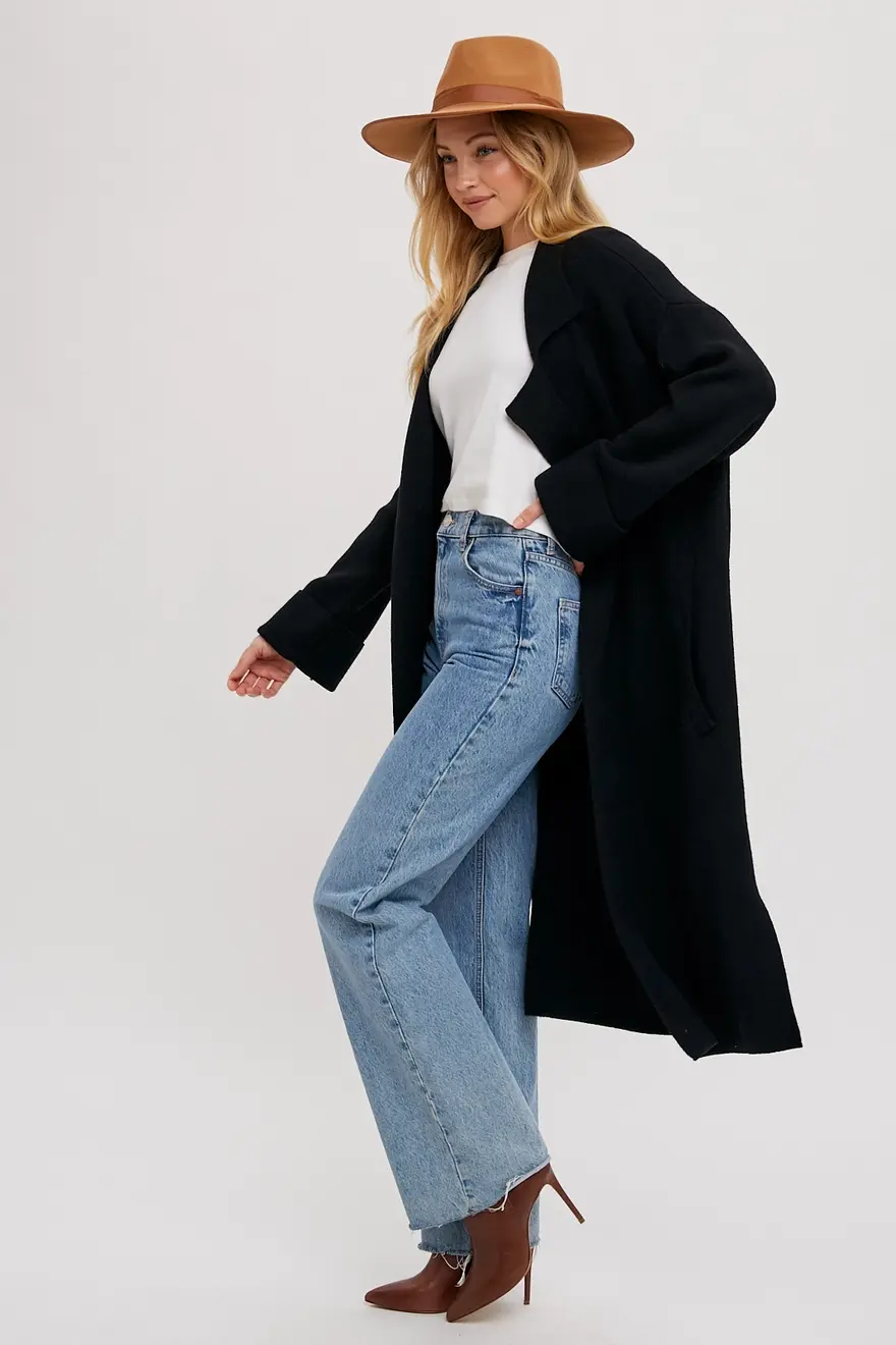 Black knit trench coat front view, oversized lapel and open styling.