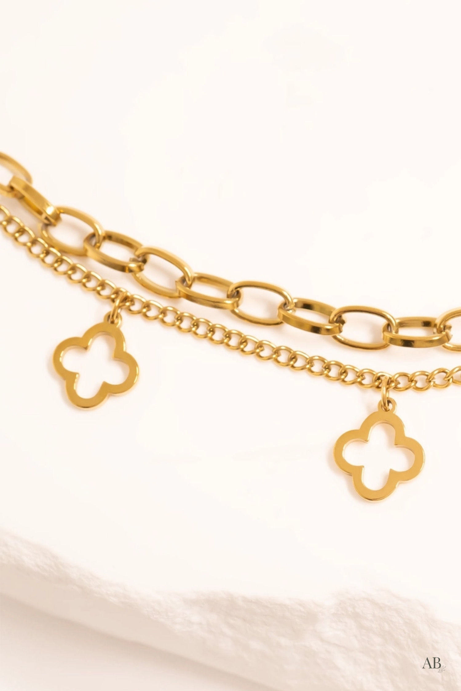 Close-up of a hypoallergenic gold layering bracelet with open clover charms for sensitive skin