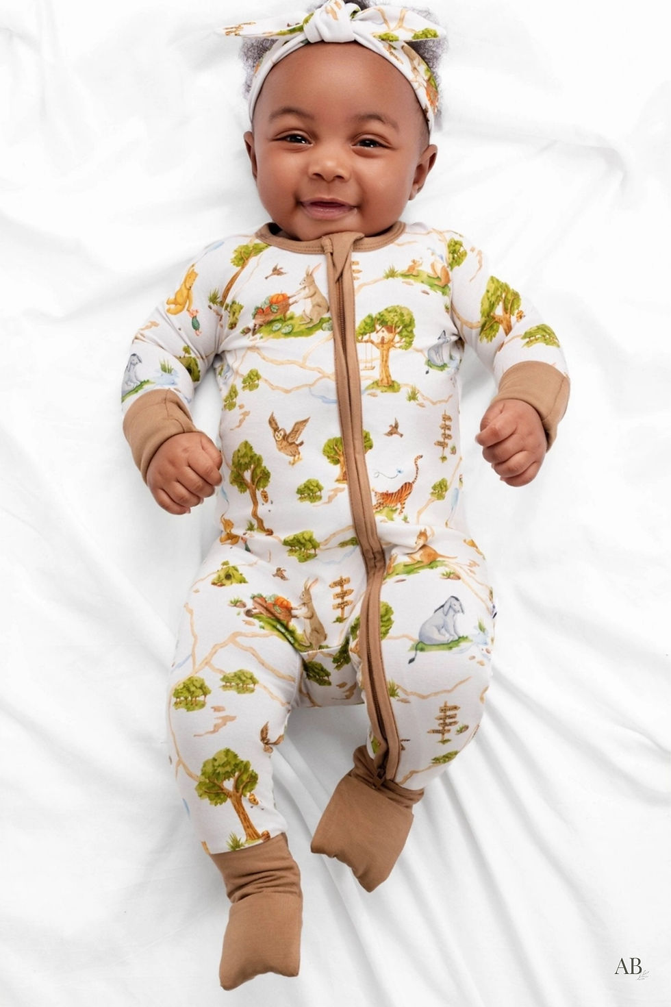 Smiling baby lying down in the Winnie the Pooh infant bamboo zip sleeper.