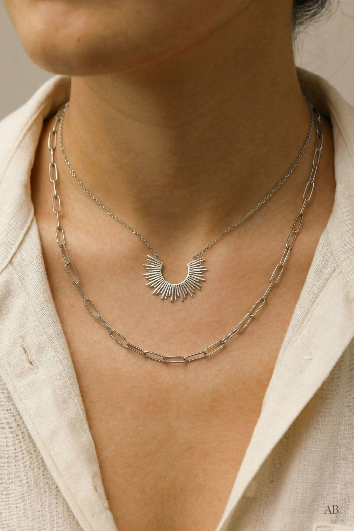 Model wearing a tarnish-free silver layered sunburst necklace with an unbuttoned linen shirt.