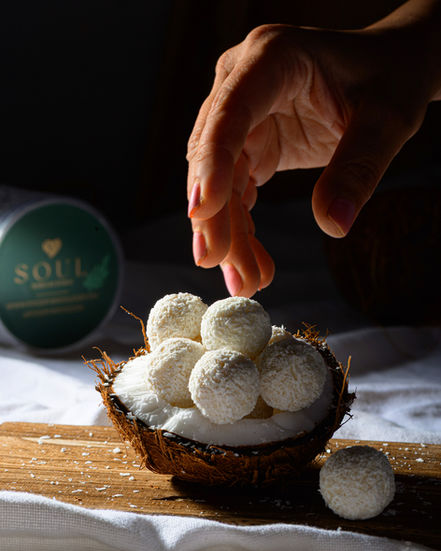 Coconut truffle balls inside a halved coconut, moody food photography