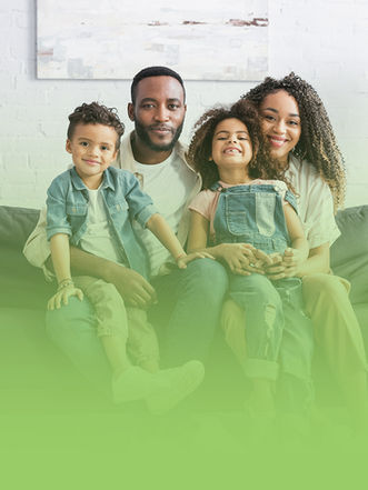 Happy Black family of four smiling on a comfortable living room couch.