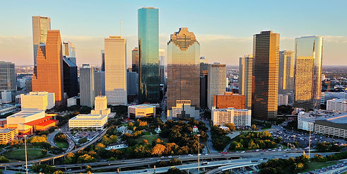 Houston city skyline with tall skyscrapers, park, and highway at sunset.