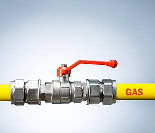 Yellow gas pipe with valve on grey background with copy space. Gas transportation system.