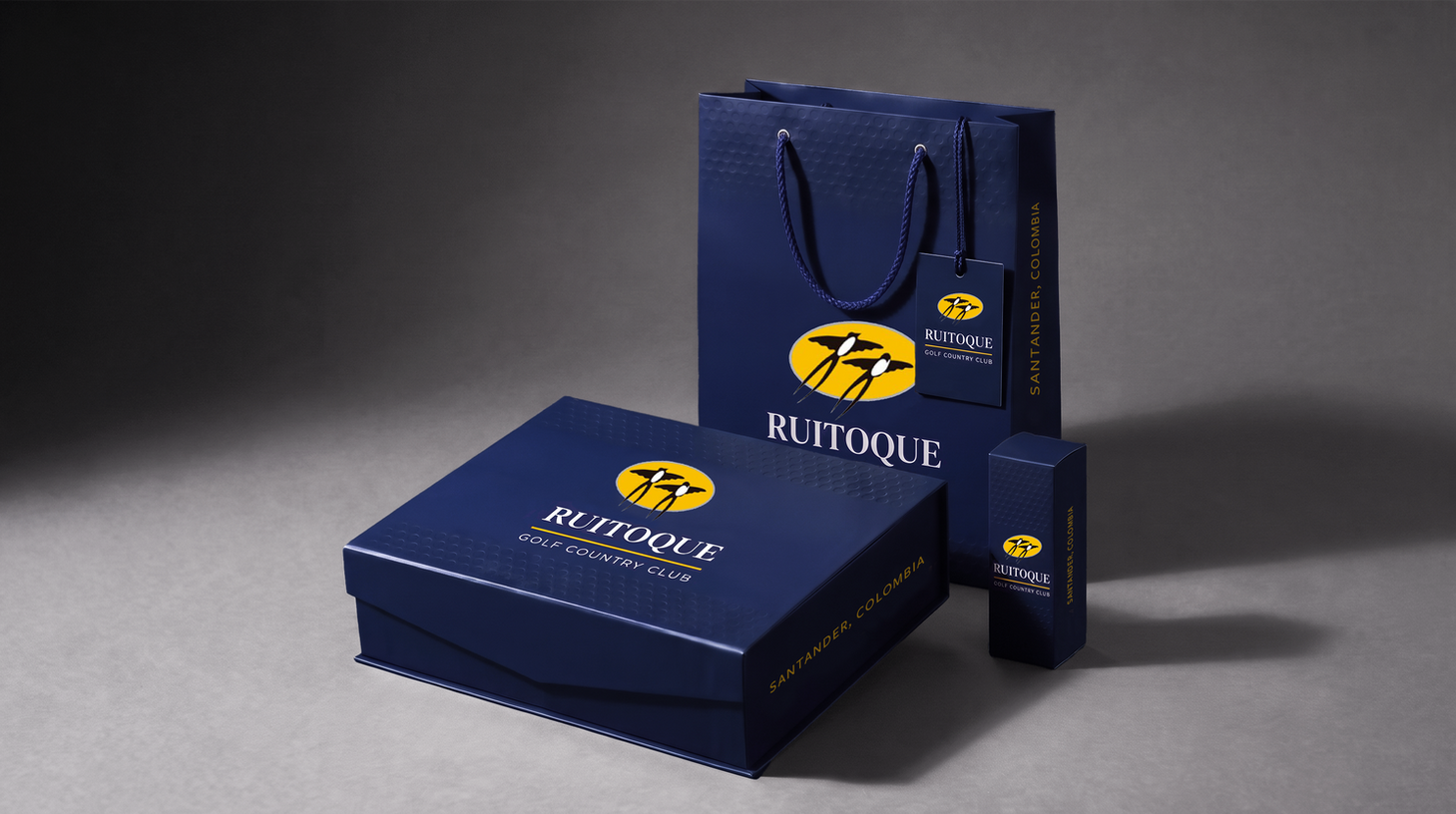 Ruitoque Golf Country Club rebrand: navy packaging set with gift box, shopping bag, hang tag and slim box on a dark backdrop