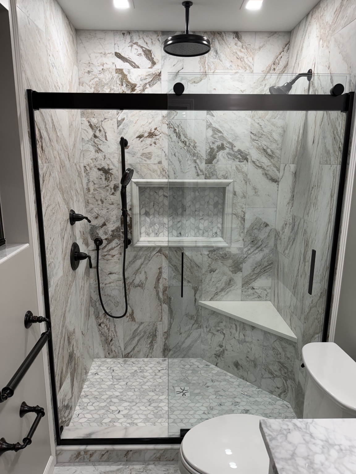 Custom shower remodel featuring marble-look tile, glass enclosure and detailed finishes