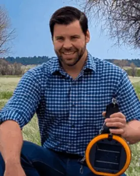 Man seated holding eShepard virtual fencing collar