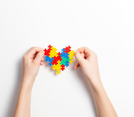 Two hands holding autism logo puzzle heart