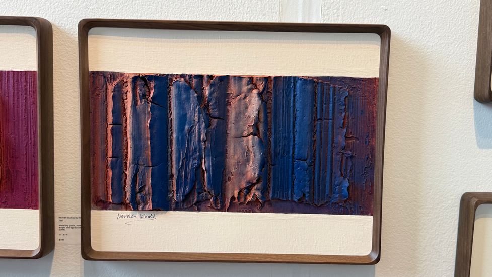 a framed painting of a blue and red landscape by a man named khalid
