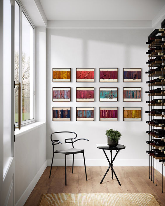 a row of paintings hang on a wall above a table