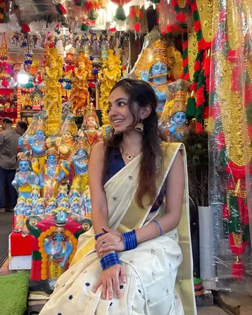 Swetha wearing Blue Grape Embroidery Tussel Tissue Kuthampully Saree with traditional makeup, visiting Guruvayur temple