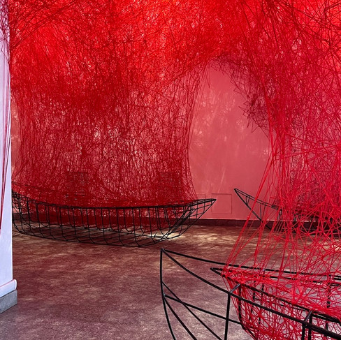 Installazione artistica di Chiharu Shiota con fitta rete di fili rossi che avvolge strutture di barche nere in una sala del MAO di Torino.