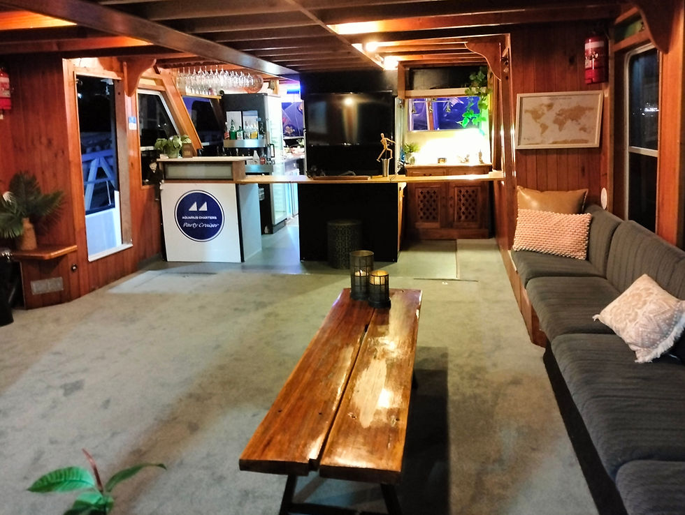 The lounge area aboard Aquarius Charters' boat offers a luxurious and welcoming cigar lounge feel, p