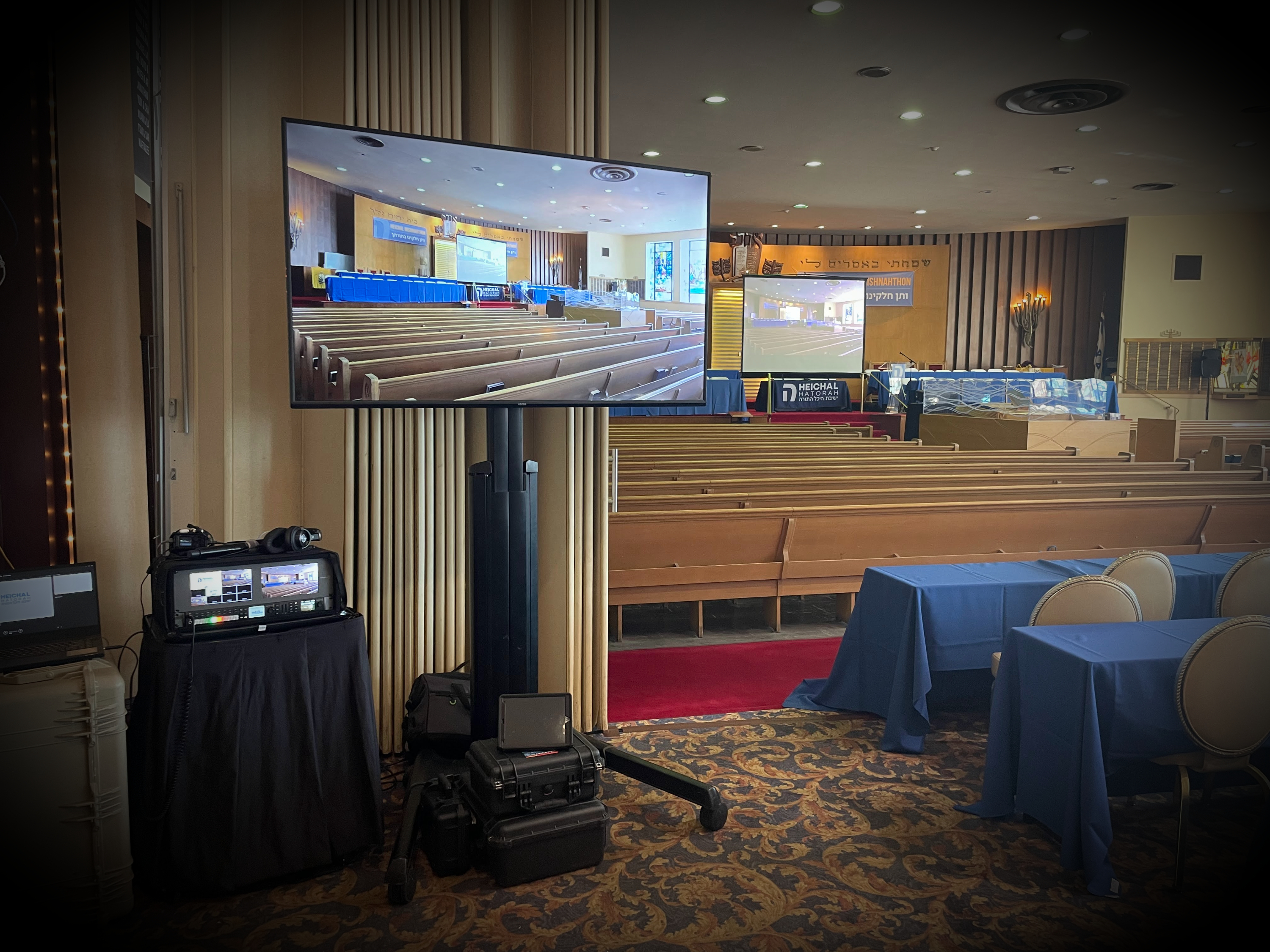 Large synagogue with full professional AV setup including cameras, projection screens, and sound system for a Lakewood community event