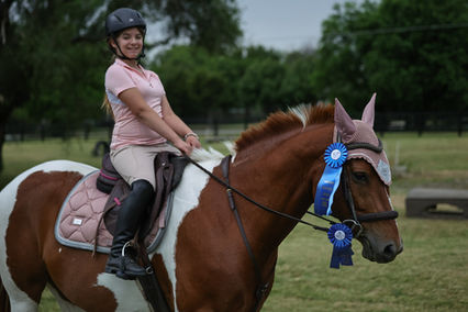 Young rider on horse with blue ribbons