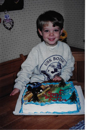 Zach stands behind a cake for his birthday celebration.