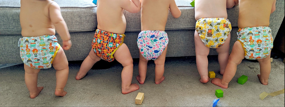 Babies stood up wearing different reusable nappies