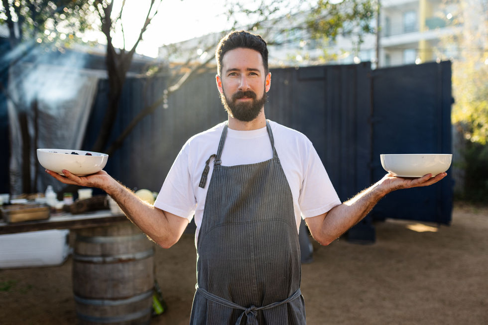 a man in an apron holds two bowls in his hands