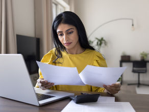 Young woman reviewing bills and financial documents while organizing estate finances.