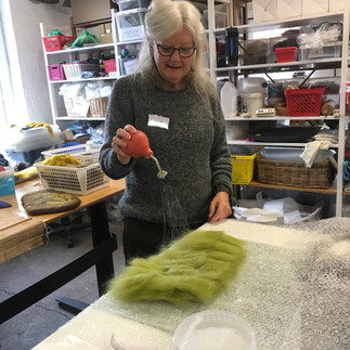 A woman is adding water to some green wool