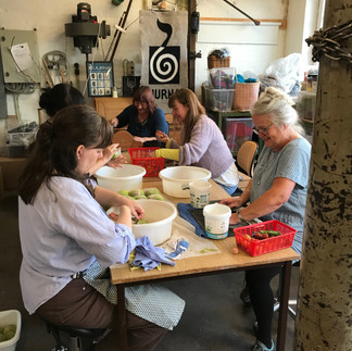 A group of people sitting by a table and felting