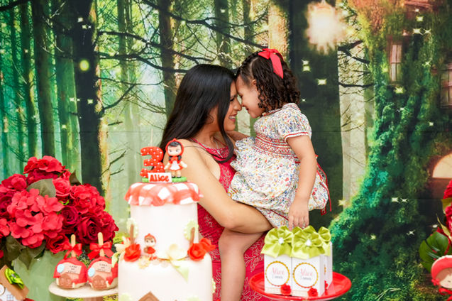 Mãe e filha, a aniverssariante, fotografam junto à mesa decorada com tema de fábula, no espaco de festa infantil Aquarella Park na zona Sulde São Paulo