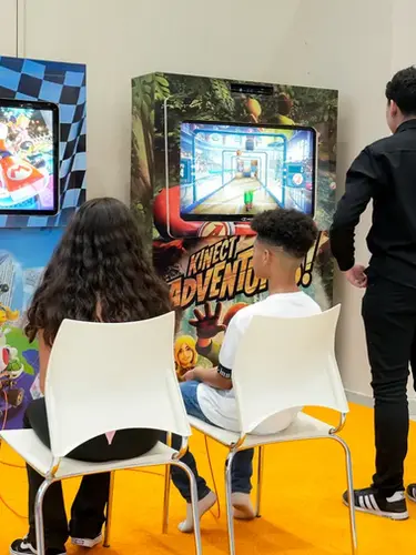 Crianças e adultos se divertem jogando videogames no espaço para festa infantil do Buffet Aquarella Park, localizado na zona sul de São Paulo