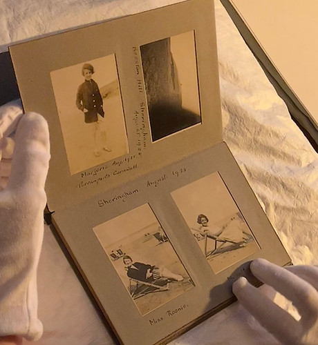 A vintage photograph album with white glove curator hands