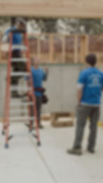construction worker wearing blue with sunglessas looking own from a ladder at his boss