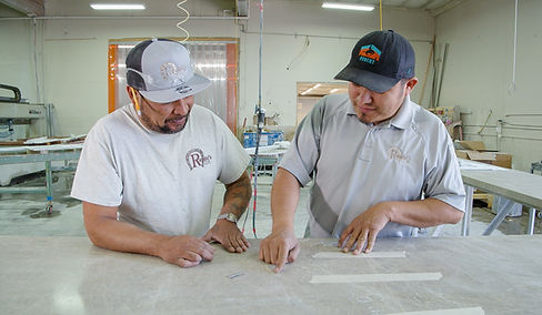 two granite fabricators talking over a slab of white granite