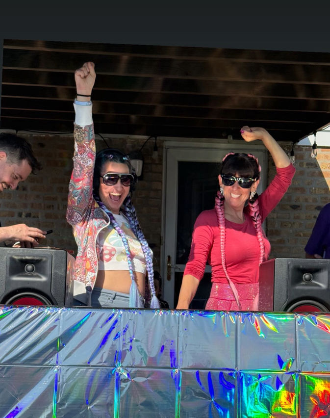 Moms with braids at the dj booth, happy and excited with their hands up