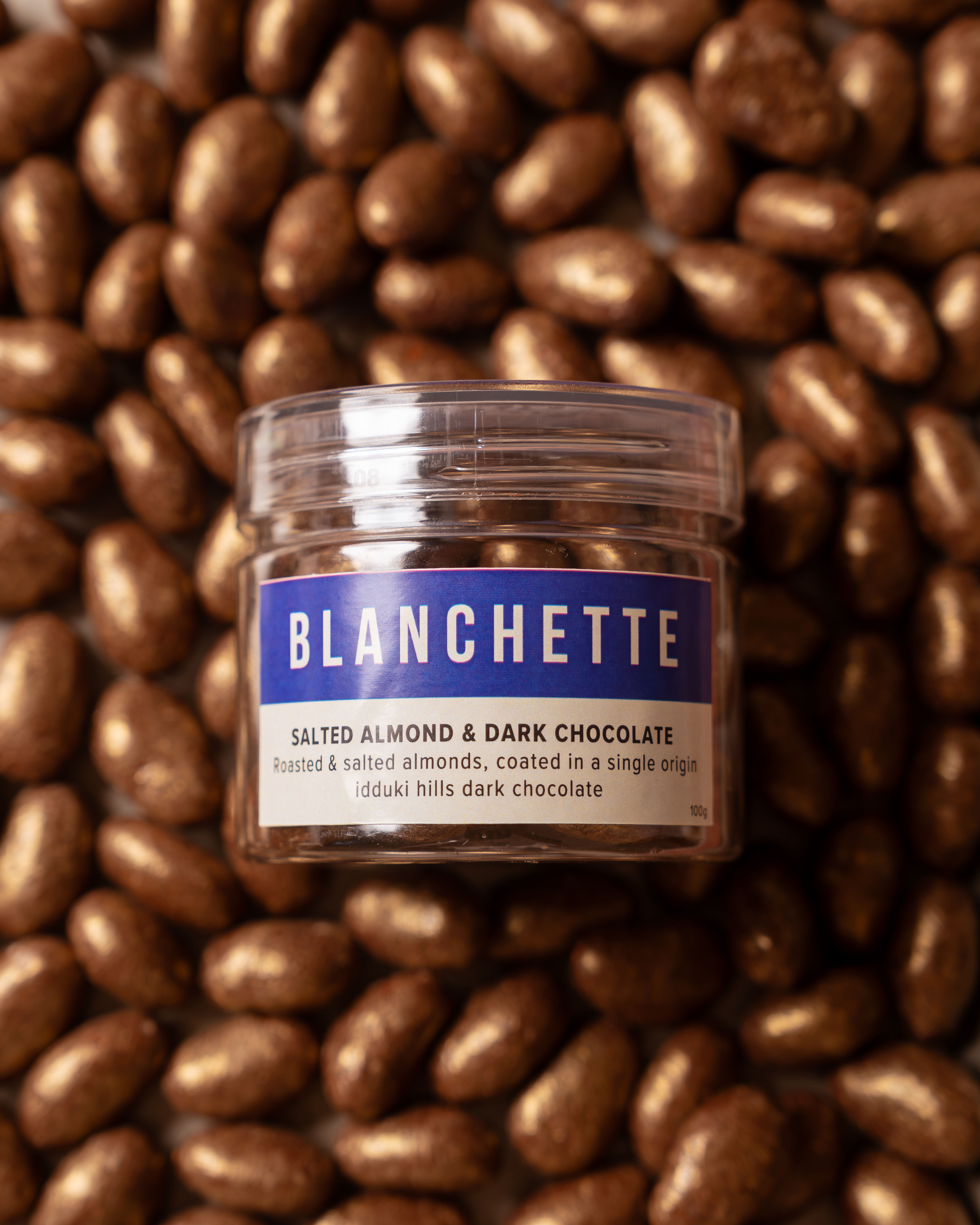 Blanchette jar of salted dark chocolate almonds on a bed of shimmer-coated almond dragées