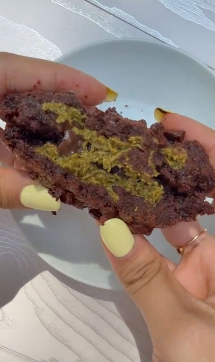 Chocolate cookie broken open to reveal a pistachio kunafa and milk chocolate centre
