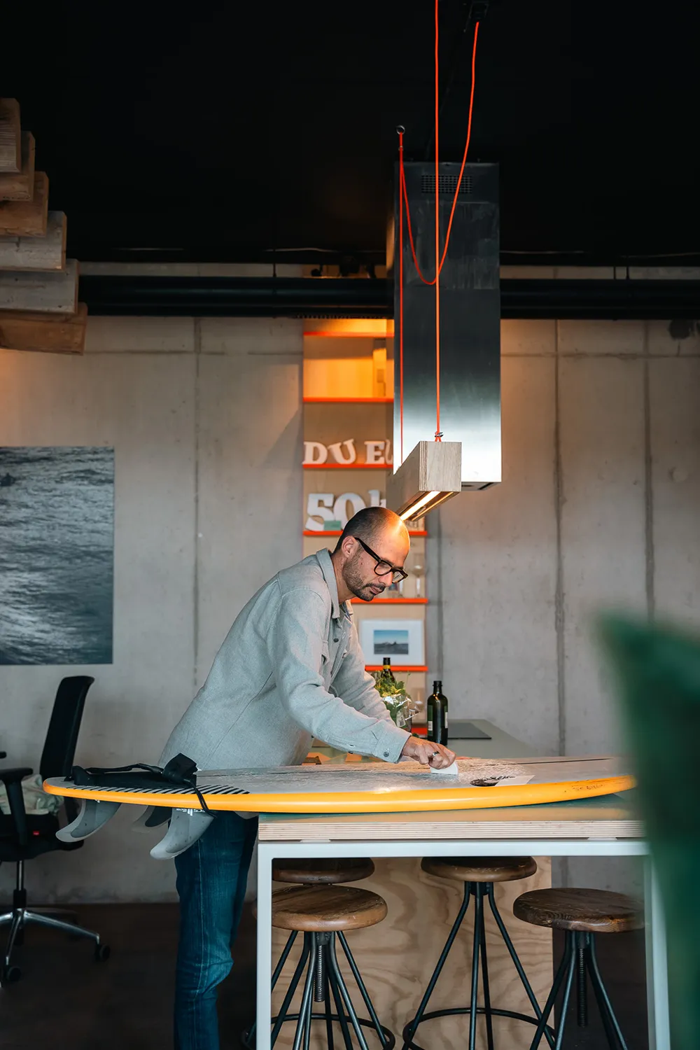 Sfeerfoto van het interieur van Studio Duel waarin Hederik zijn surfboard aan het waxen is.