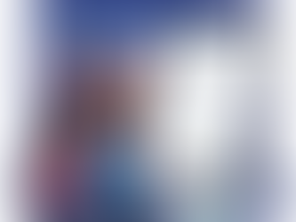 Husband and wife filling out Form I-130A (Supplemental Information for Spouse Beneficiary) on a tablet, surrounded by passports, photos, green cards, and immigration paperwork, with the Statue of Liberty in the background.